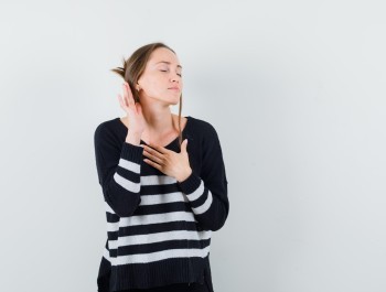 young-woman-standing-listening-pose-holding-one-hand-chest-while-closing-eyes-striped-knitwear-black-pants-looking-happy-3-_main