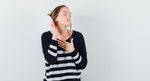 young-woman-standing-listening-pose-holding-one-hand-chest-while-closing-eyes-striped-knitwear-black-pants-looking-happy-2-_main